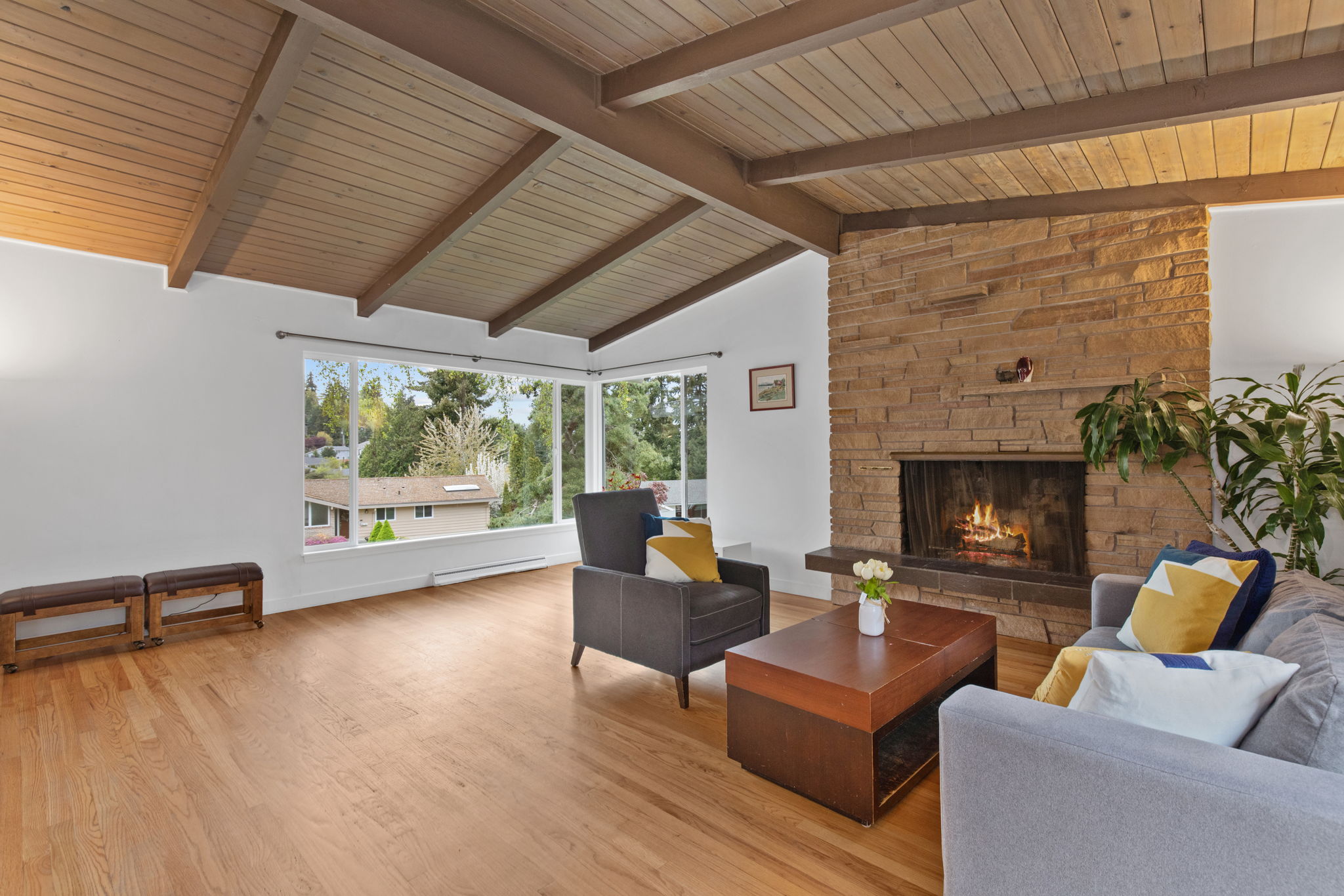 mid-century living room with large windows and natural stone fireplace
